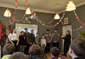 Uczniowie w strojach z epoki występują na scenie podczas apelu z okazji 11 listopada.